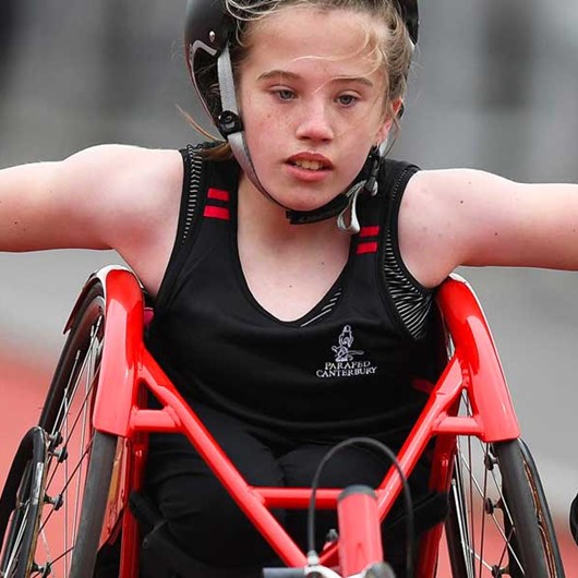 Girl pushing a racing wheelchair down the track image
