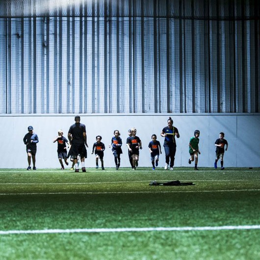 Boys and coaches warming up at an indoor sports facility image