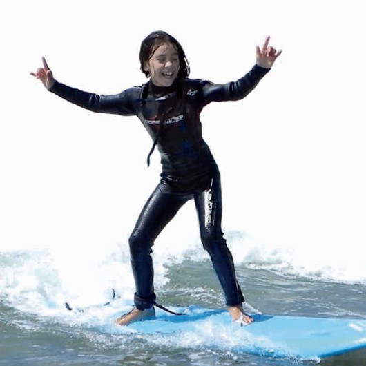 Tamariki catching a wave on surfboard image