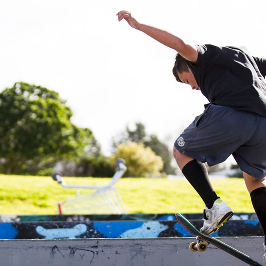Boy getting air on skateboard at skateboard park image