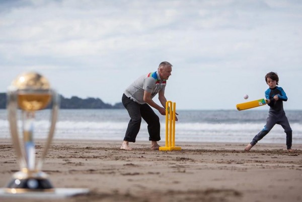 Old man and kid play beach cricket