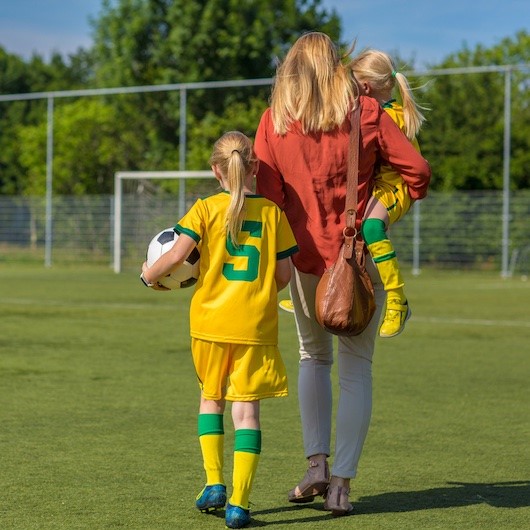 Parent looking after their two children after a soccer match image