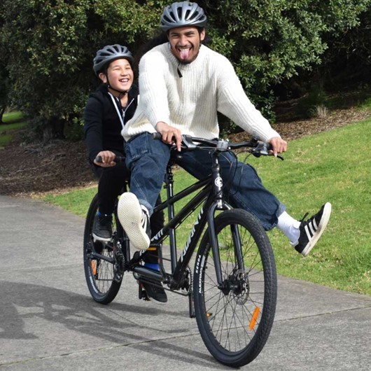 Adult and child laughing while riding a tandem bike image