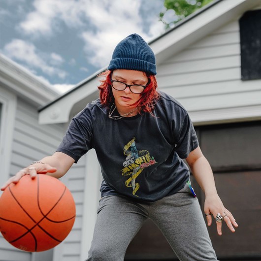 Young woman bouncing basketball in driveway image