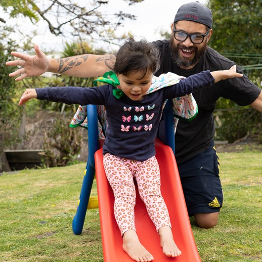 Father and daughter enjoy pretending to fly on a slide image