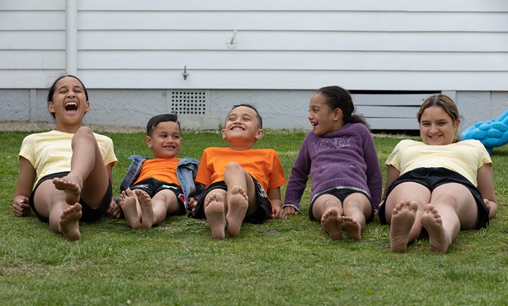 Five tamariki laughing on the lawn