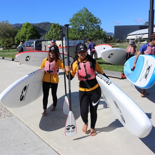 Two young women carrying paddleboards to the beach image