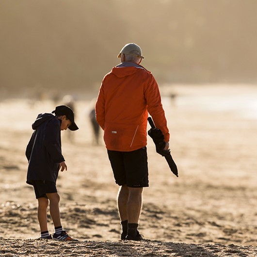 A grandfather and grandson walking together on a beach image
