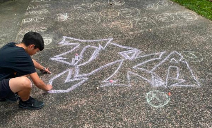 Student drawing on footpath with chalk