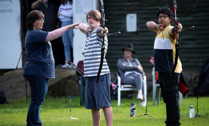 Two teenage boys pulling arrows at a target