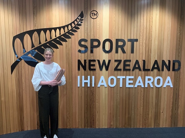 Young woman standing in front of the Sport New Zealand sign