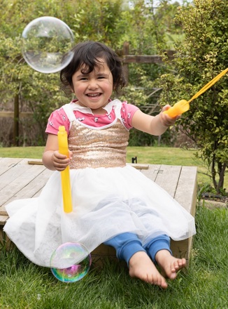 Smiling child playing with bubbles outside