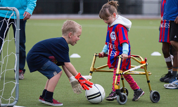 Girl with walking frame shooting for goal in soccer