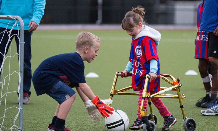 Girl with walking frame shooting for goal in soccer