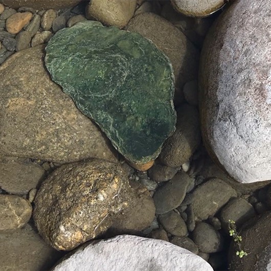 Greenstone nestled amongst river stones