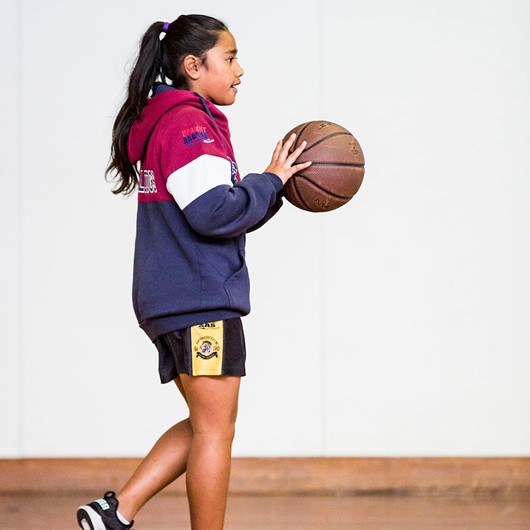 Girl bouncing a basketball at the gym