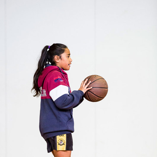 Girl bouncing a basketball at the gym