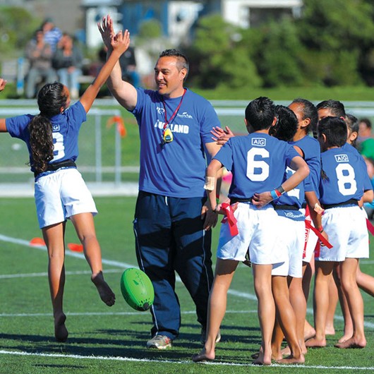 Coach hi-fives a girl after a practice rugby conversion