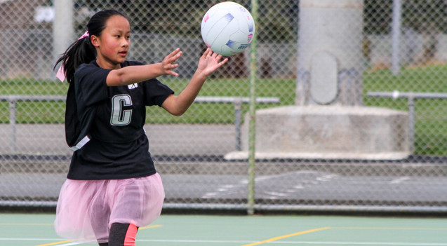 a young female netball player catching a ball