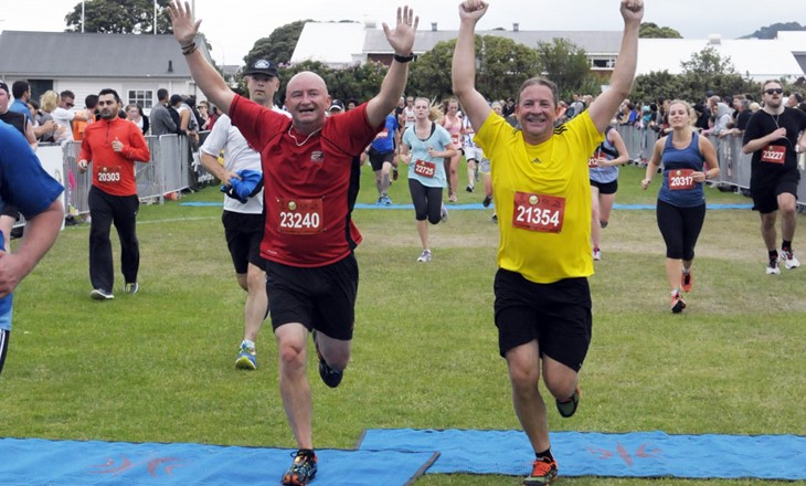 Two adults crossing a finish line in a running race