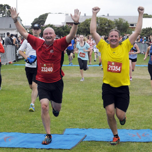 Two adults crossing a finish line in a running race image