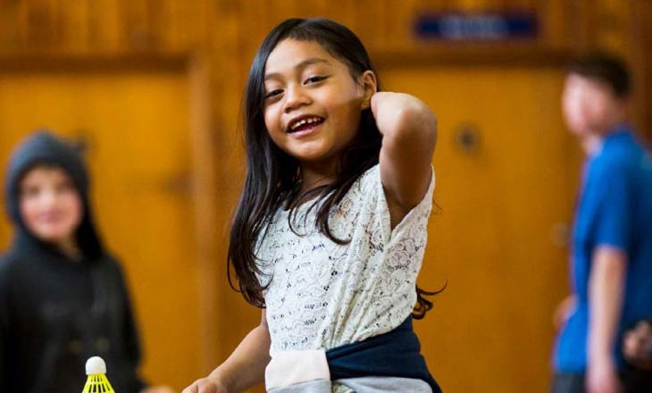 Smiling tamariki prepares to play badminton