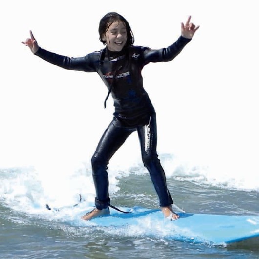 Tamariki catching a wave on surfboard
