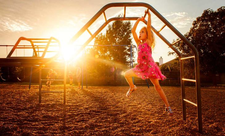 Girl having fun climbing on playground climbing bars