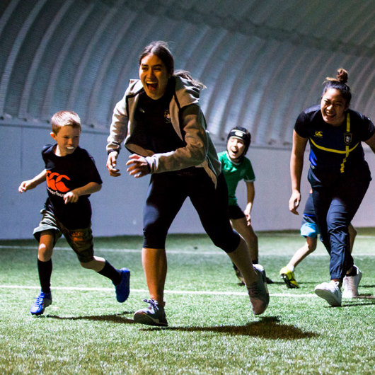 Volunteers and young team smiling and running at indoor club