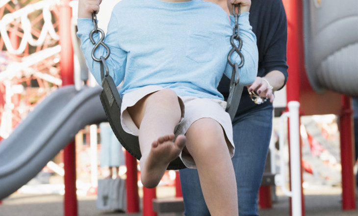 Smiling mum pushing a child on a swing