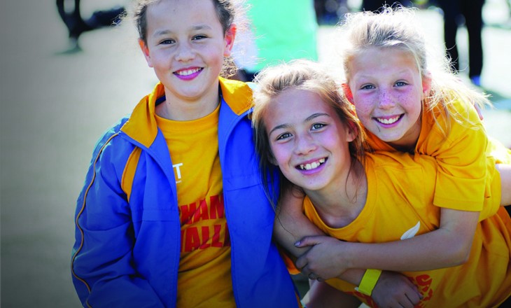 Three smiling girls dressed to participate