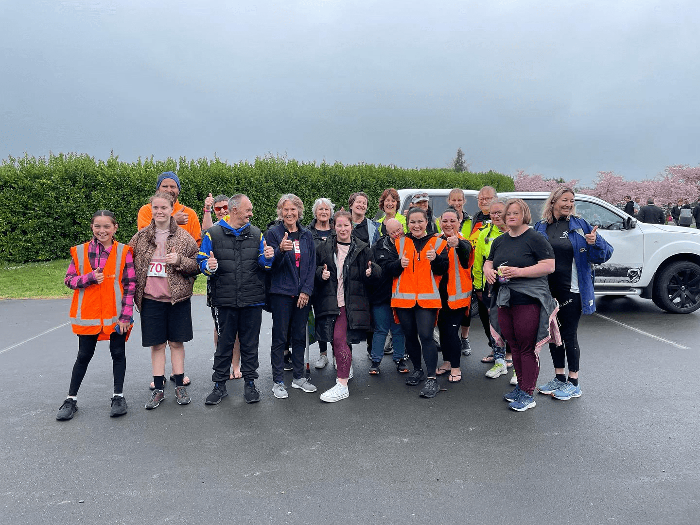 Group of people looking to camera giving a thumbs up gesture