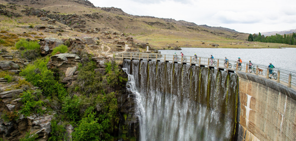 Distant view of cyclists riding across a dam bridge