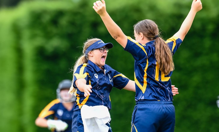Female cricket fielders cheer victoriously