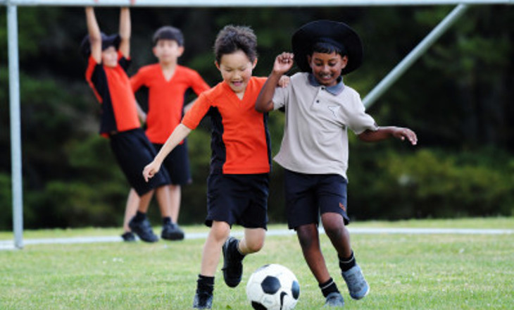 Two boys in a friendly tussle to get control of soccer ball