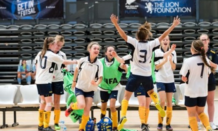 Two female futsal teams clapping on court after a game.
