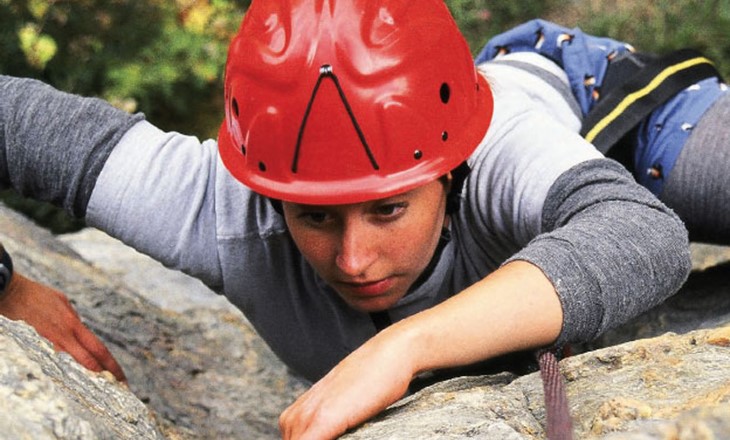 Girl in hard hat climbing a rock face