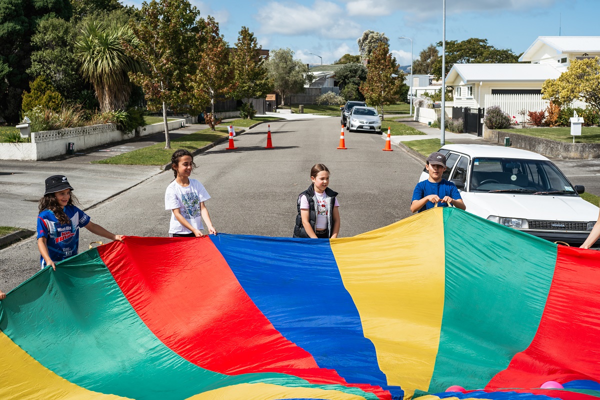 Tamariki playing with a parachute on a street