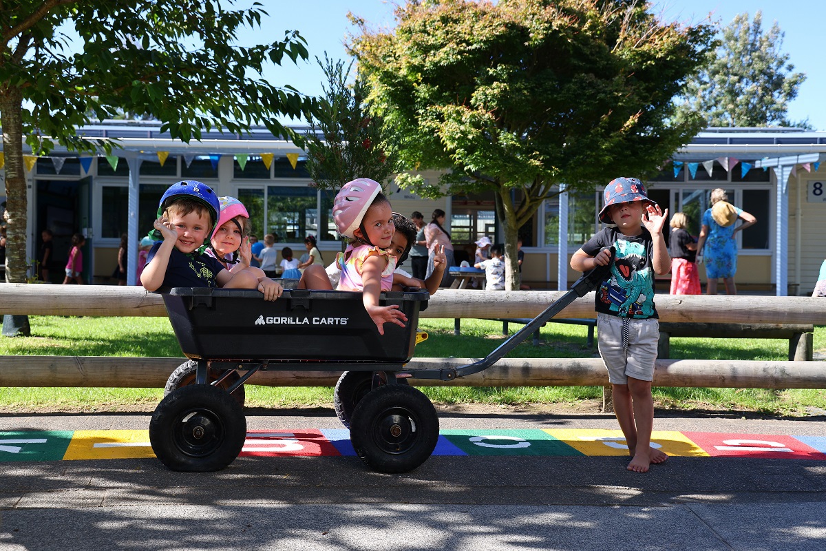 Kids in a large wheel barrow pulled by another child