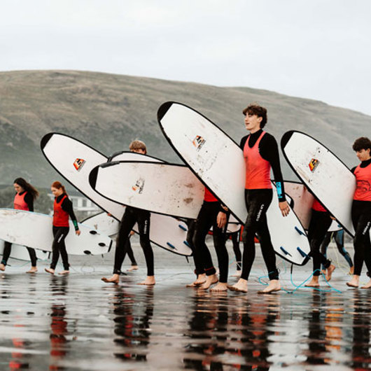 Rangatahi surfers walking towards the surf
