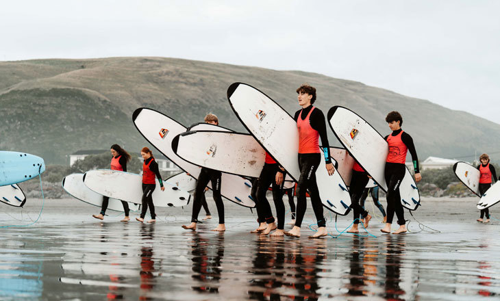 Rangatahi surfers walking towards the surf