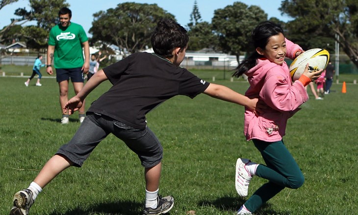 Boy tags a girl during a game of touch rugby