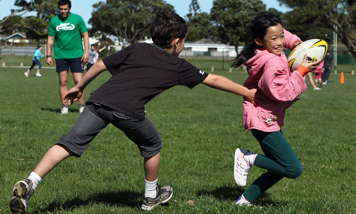 Boy tags a girl during a game of touch rugby