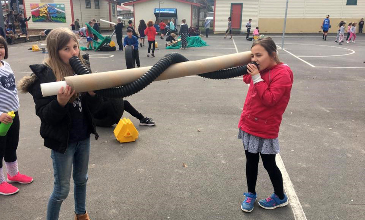 Children on courts playing with cardboard and plastic pipes