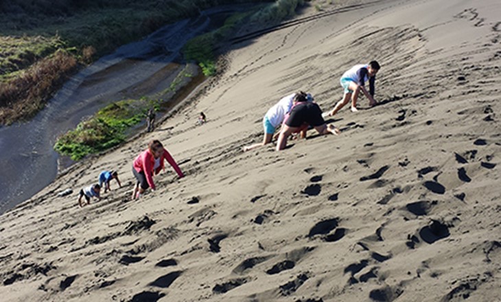 A group climbing steep sand dunes