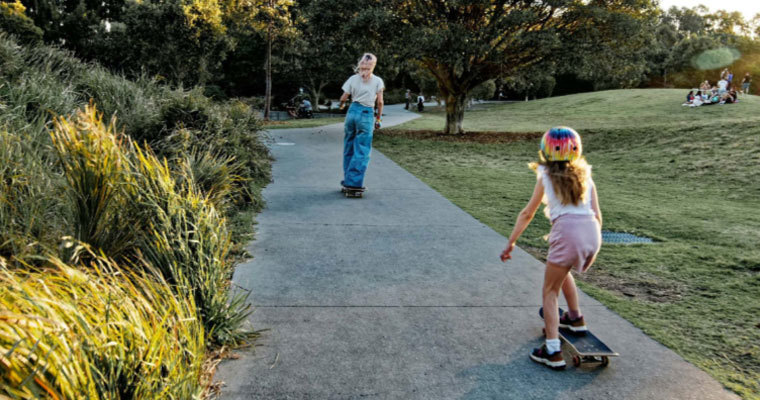 Tamariki skateboarder follows an older skater along a path