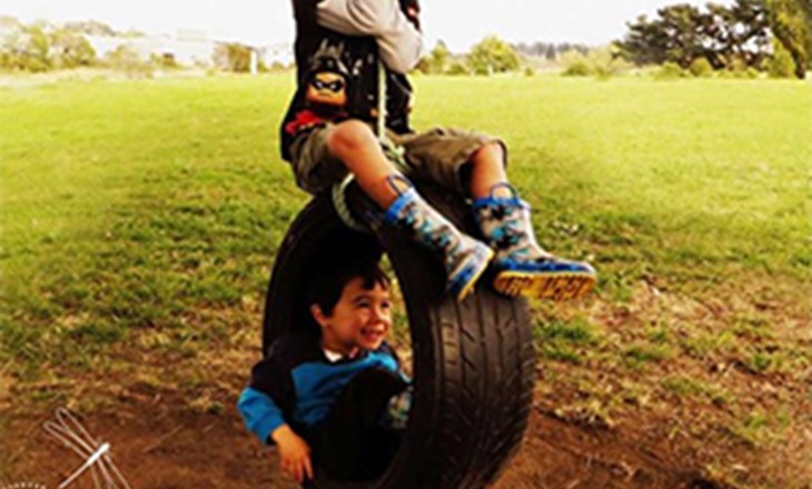 Two boys playing on a tire swing