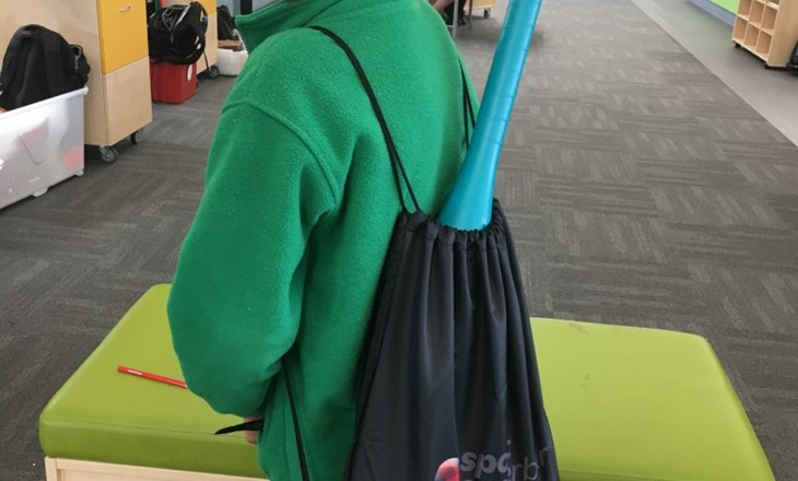 A boy smiling with a baseball bat in his bag