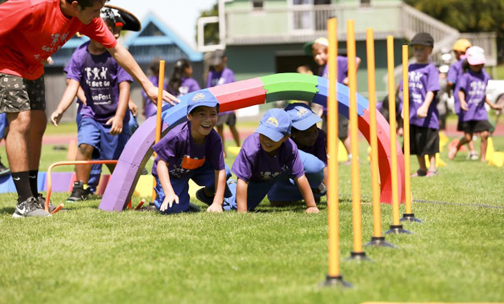 Kids crawling under an obstacle on a field 