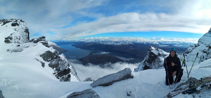 A graduate sitting on top of a snow capped mountain